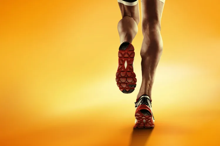 Low angle view of a male runner's legs running down the road wearing trainers
