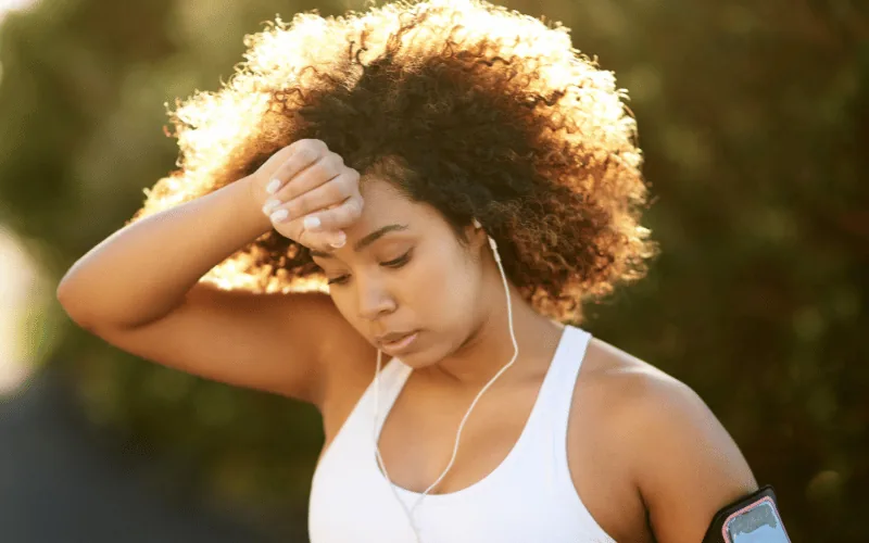 Young woman wiping her brow during her workout