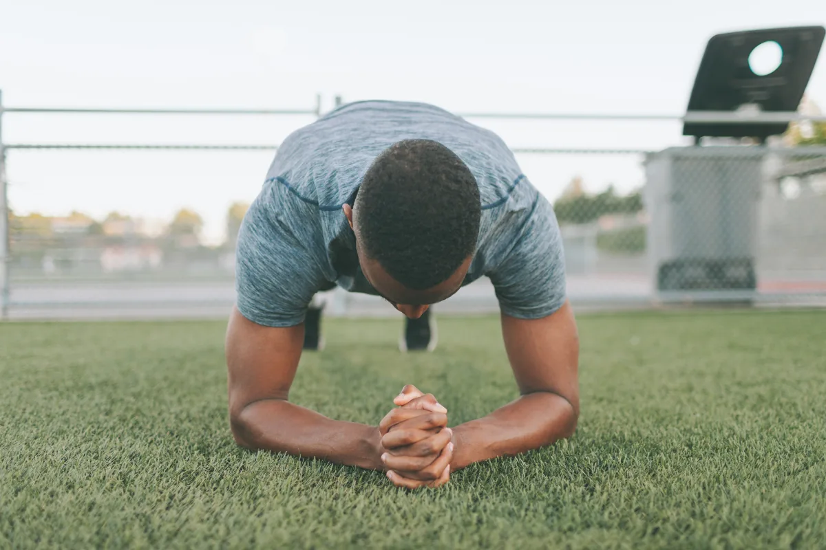 Runner holding a forearm plank on grass