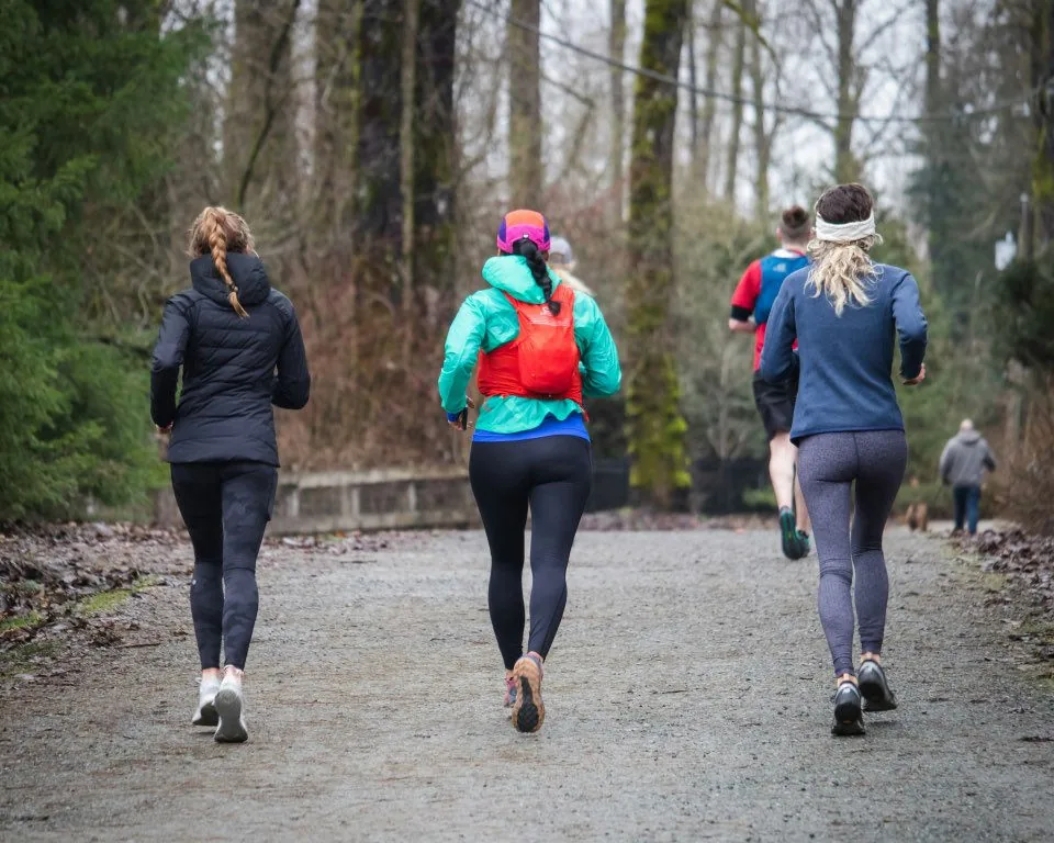Three women running together in a winter forest
